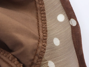Vue macro détaillée du tissu mousseline marron à pois et texture des coutures