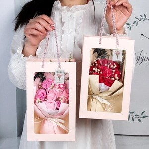 Detail of soap flower gift box with roses and carnations held in pink carry bags