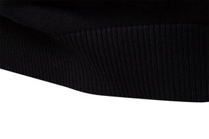 Vue macro du tissu en maille côtelée noire montrant la texture détaillée du pull en coton