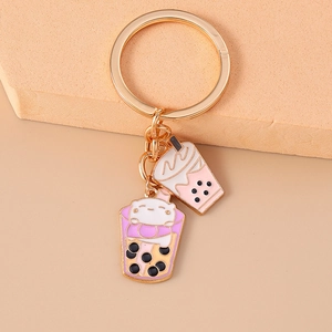 Close-up of golden keychain featuring pink bubble tea charms and a cartoon cat pendant