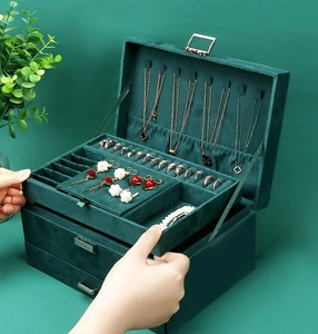 Three-layer dark green velvet jewelry box showing internal compartments and metal lock