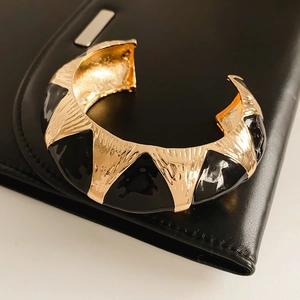Detail of vintage oval cuff bracelet with black enamel triangles and gold brushed metal finish
