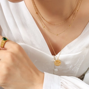 Three-layer gold necklace with round Good Luck pendant and bead chain detail
