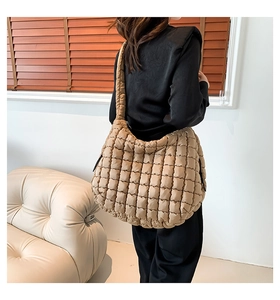 Close-up of khaki quilted puffy tote bag showing padded nylon texture and wide strap
