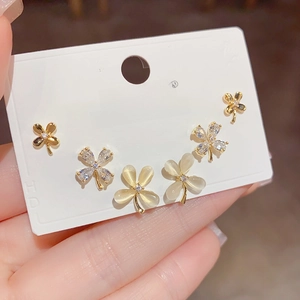 Macro detail of gold-plated clover earrings set with cat's eye stone and cubic zirconia