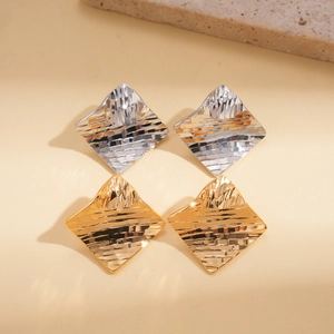 Detail of 18k gold and silver plated rhombic earrings with textured metal surface
