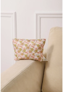 Close-up of a floral cosmetic bag with pink and green patterns on a soft fabric sofa