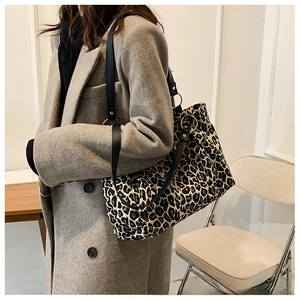 Detail of leopard print canvas tote with black leather straps and metal ring connector