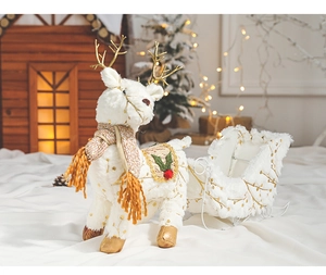 Close-up of white plush reindeer with gold glitter dots and yellow scarf by a mini sleigh