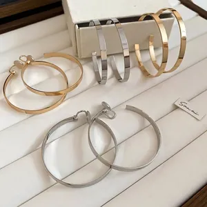 Polished silver and gold round hoop earrings set on a white jewelry display tray