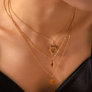 Three-layer gold necklace with sun and star pendants worn by a model on the neck