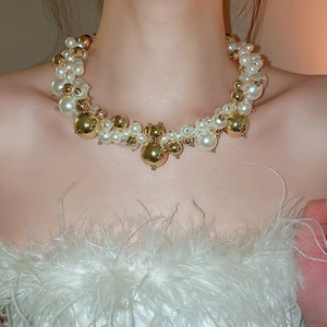 Close-up of elegant French pearl and gold bead necklace worn by model on a white feather dress