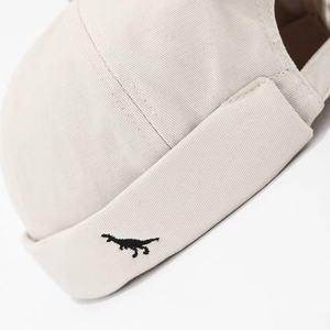 Beige cotton docker hat with minimalist black dinosaur embroidery in street style