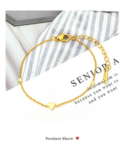 Close-up of golden stainless steel chain bracelet with three polished heart pendants