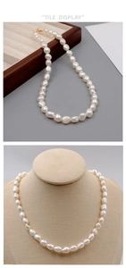 Detail of baroque pearl necklace with golden lobster clasp on display tray and neck model