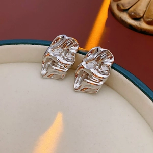 Detailed close-up of irregular silver stud earrings with a liquid lava texture finish