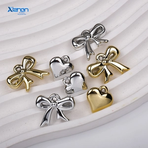 Detailed view of gold and silver plated metal bow and heart charms for DIY jewelry making