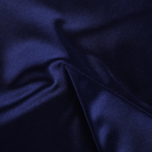 Gros plan du tissu satiné bleu foncé montrant le drapé lisse et le tissage sergé