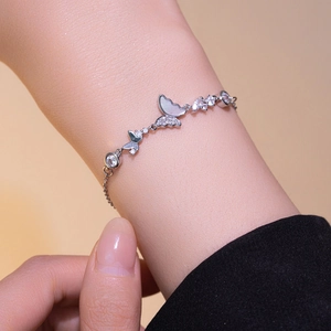 Silver butterfly bracelet with shell and zircon stones shown on a woman wrist