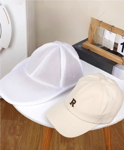 Close-up of a white mesh laundry bag with support frame for baseball caps in a laundry room