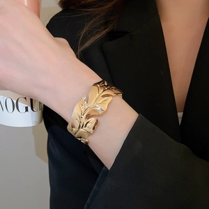 Macro shot of a golden leaf-shaped cuff bracelet with realistic vein texture on a wrist