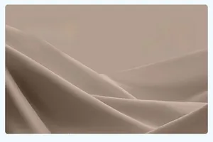 Dettaglio del tessuto leggero traspirante color terra con morbide pieghe e trama