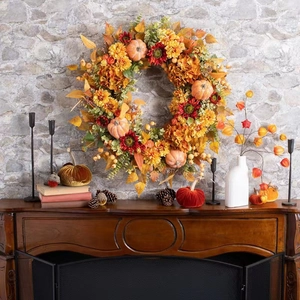 Autumn harvest wreath with orange pumpkins and colorful hydrangea on rustic fireplace