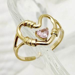 Macro detail of a gold chain ring featuring a radiant pink heart-shaped gemstone