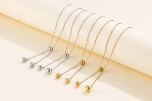 Detail of gold and silver stainless steel necklaces with matte and polished bead pendants