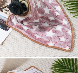 Close-up of a soft pink star-patterned pet blanket wrapped around a pug on a rug