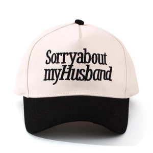 Nahaufnahme der Stickerei Sorry About My Husband auf einer beige-schwarzen Trucker-Mütze