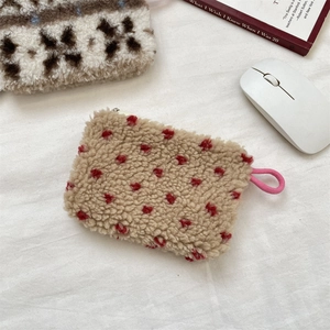 Macro shot of plush cream faux shearling storage pouch with red dots and pink lanyard