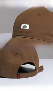 Detail view of brown baseball cap featuring cloth label and adjustable back buckle