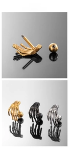 Detail of punk style skull hand ear studs showing threaded ball ends and textures