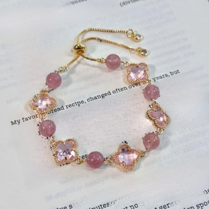 Bracelet ajustable élégant trèfles roses et perles dorées sur fond de livre décoratif