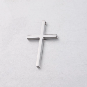Close-up of polished silver stainless steel cross pendant on white textured surface