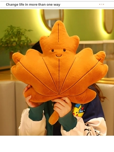 Detail of orange maple leaf plush cushion with smiling face texture and soft fabric