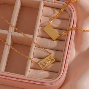 Close-up of gold 11:11 rectangle pendant necklaces in a pink velvet jewelry box