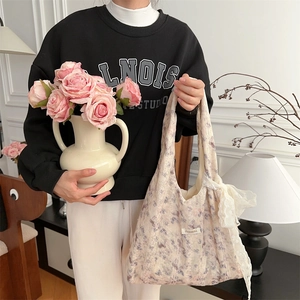 Detail of floral lace tote bag with bow accent and delicate lavender flower patterns