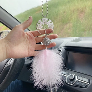 Pink Tree of Life car charm with crystal stones and soft feathers hanging in a car interior