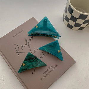 Triangle marble texture hair clips in blue-green resin with gold accents on book