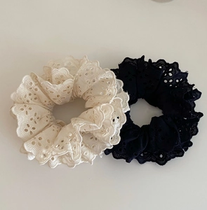 Close-up of cream and black lace hair scrunchies with intricate hollowed flower patterns