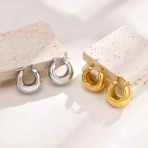 Macro detail of thick hollow hoop earrings in gold and silver finish on stone