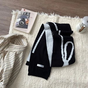 Flat lay of a black and white bow jacquard knit scarf with stylish lifestyle props