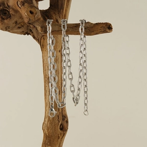 Textured stainless steel O-chain necklace with lobster clasp hanging on a wooden branch