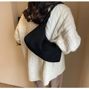 Detailed back view of a black suede crescent shoulder bag with golden buckle on a model