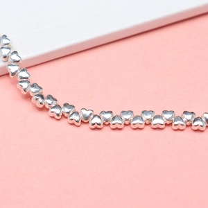 S925 sterling silver heart-shaped spacer beads for bracelets on a pink background