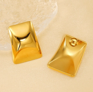 Macro de boucles d'oreilles rectangulaires en or poli sur fond de soie texturé