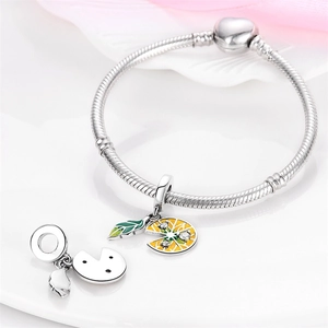 Detailed close-up of a silver charm bracelet featuring a yellow enamel lemon slice pendant