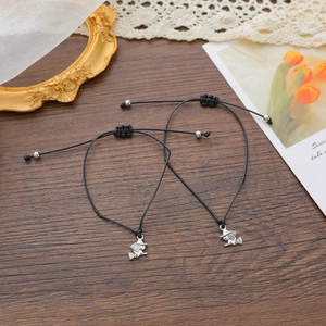 Adjustable black rope bracelets with silver witch pendant on vintage wood surface